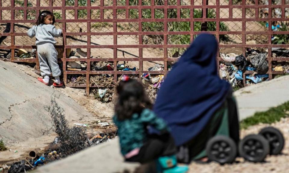 A woman sits with her child on the ground at camp al-Roj, in Syria