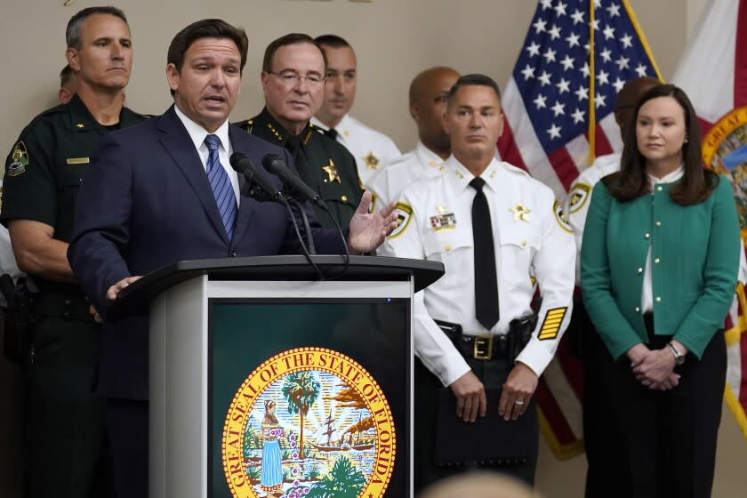 Florida Gov. Ron DeSantis, surrounded by members of law enforcement, gestures as he speaks during a news conference Thursday, Aug. 4, 2022, in Tampa, Fla. DeSantis announced that he was suspending State Attorney Andrew Warren, of the 13th Judicial Circuit, due to "neglect of duty." Looking on at right is Florida Attorney General Ashley Moody. (AP Photo/Chris O'Meara)