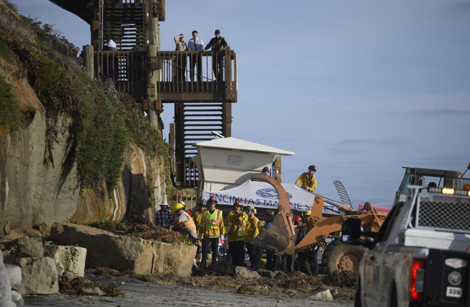 Search and rescue personnel work at the site of a cliff collapse at a popular beach Friday, Aug. 2, 2019, in Encinitas, Calif. At least one person was reportedly killed, and multiple people were injured, when an oceanfront bluff collapsed Friday at Grandview Beach in the Leucadia area of Encinitas, authorities said. (AP Photo/Denis Poroy)