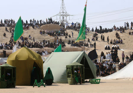 Iraqi people behind tents watch the local actors dressed as ancient warriors re-enact a scene from the 7th century battle of Karbala to commemorate Ashura in Najaf, September 20, 2018. REUTERS/ Alaa Al-Marjani