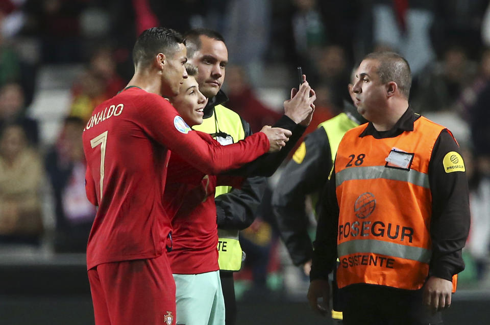 Portugal's Cristiano Ronaldo, left, takes a selfie with a young fan at the end of the Euro 2020 group B qualifying soccer match between Portugal and Ukraine at the Luz stadium in Lisbon, Friday, March 22, 2019. (AP Photo/Armando Franca)