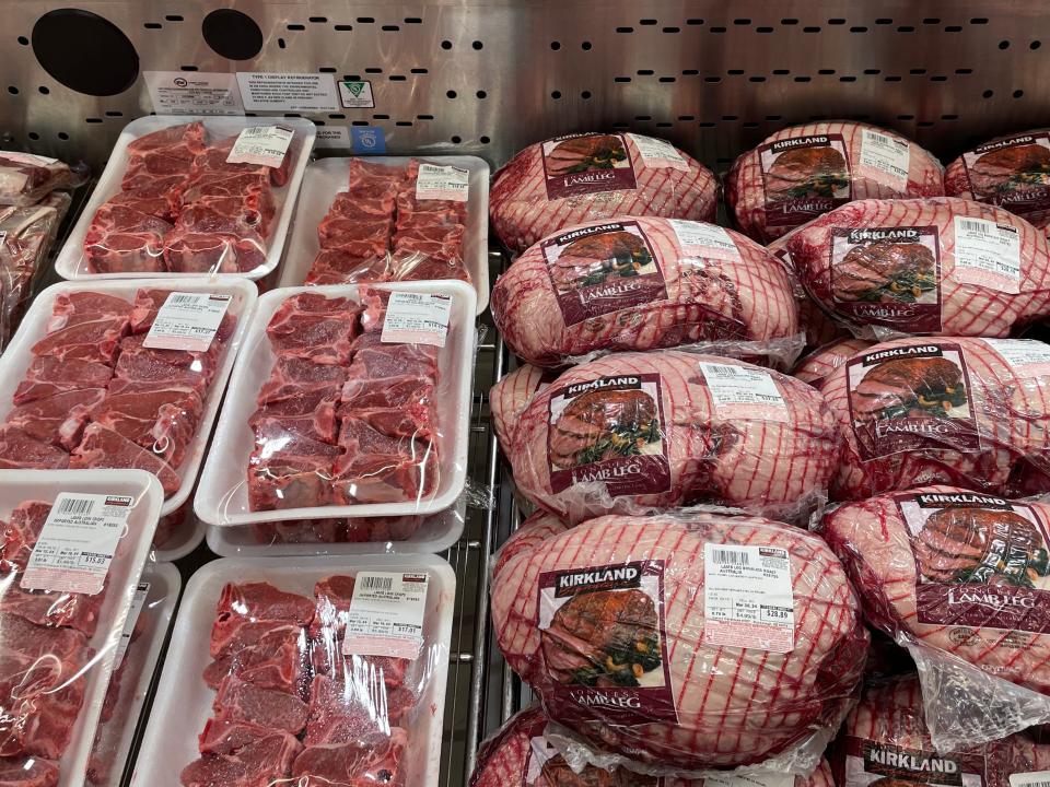Clear plastic trays of lamb loin chops next to packages of lamb leg roasts in refrigerated section at Costco