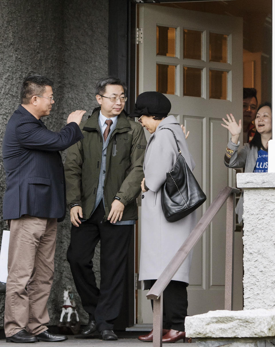 Huawei chief financial officer Meng Wanzhou, right, waves goodbye to visitors at her home in Vancouver on Wednesday, Dec. 12, 2018. A Canadian court on Tuesday released Meng on bail, confining her to Vancouver and its suburbs while she awaits possible extradition to the United States. The U.S. has accused Huawei, the biggest global supplier of network gear for phone and internet companies, of using a shell company to do business with Iran in violation of U.S. sanctions. (Jonathan Hayward/The Canadian Press via AP)