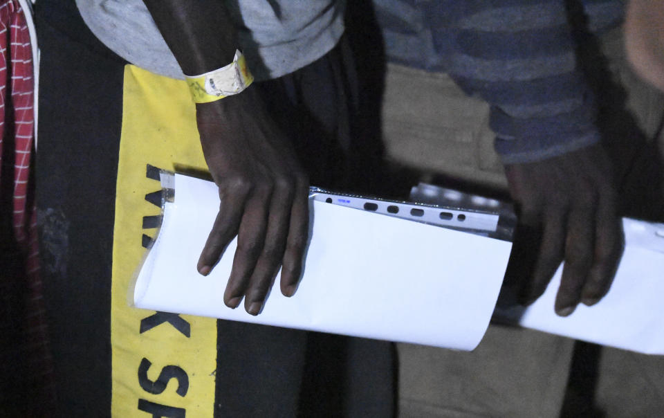 Two migrants on the Open Are ship hold files before disembarking on the Sicilian island of Lampedusa, southern Italy, Tuesday, Aug. 20, 2019. An Italian prosecutor ordered the seizure of a rescue ship and the immediate evacuation of more than 80 migrants still aboard, capping a drama Tuesday that saw 15 people jump overboard in a desperate bid to escape deteriorating conditions on the vessel and Spain dispatch a naval ship to try to resolve the crisis. (AP Photo/Salvatore Cavalli)