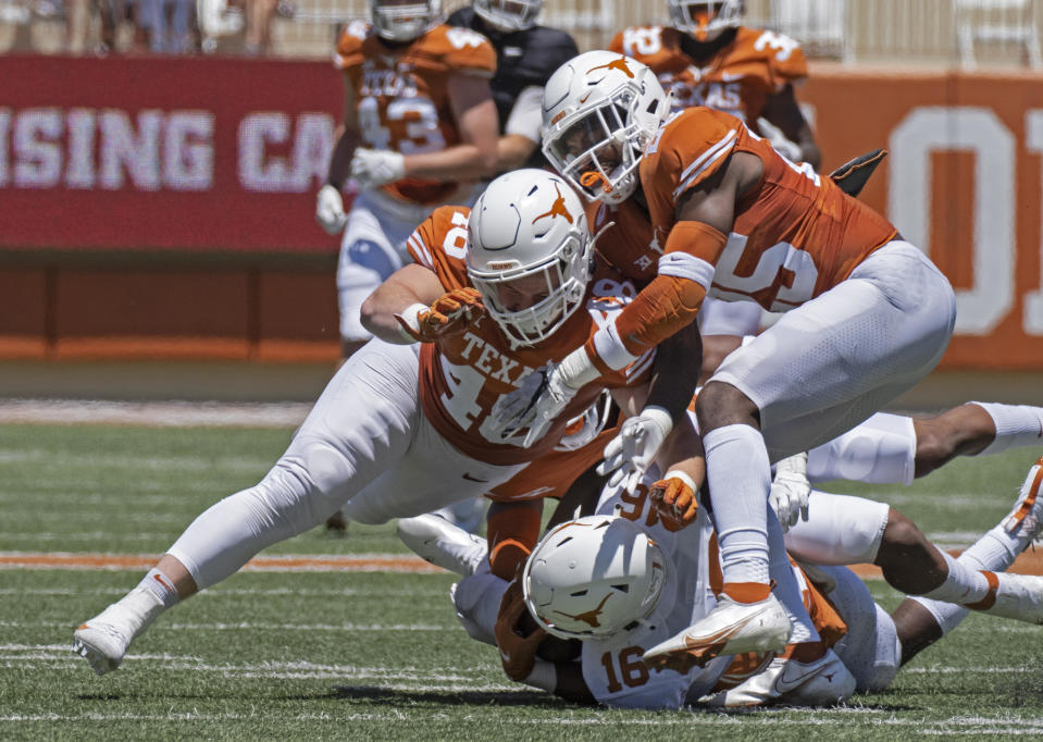 April 24, 2021 file photo shows Texas defenders Jake Ehlinger, left, and B.J. Foster, right, tackling Kayvontay Dixon (16) during the first half of the Orange and White spring scrimmage college football game in Austin, Texas. / Credit: Michael Thomas / AP