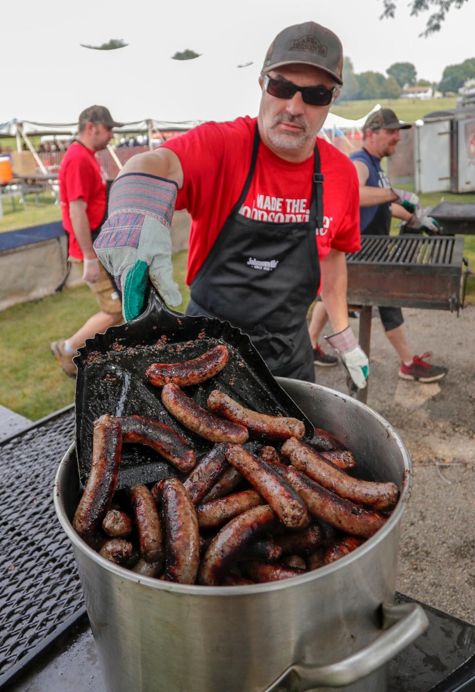 Mark Kreutz, of Sheboygan, shovels brats into a big holding pot during Brat Days at Kiwanis Park, Saturday, Aug. 7, 2021, in Sheboygan.