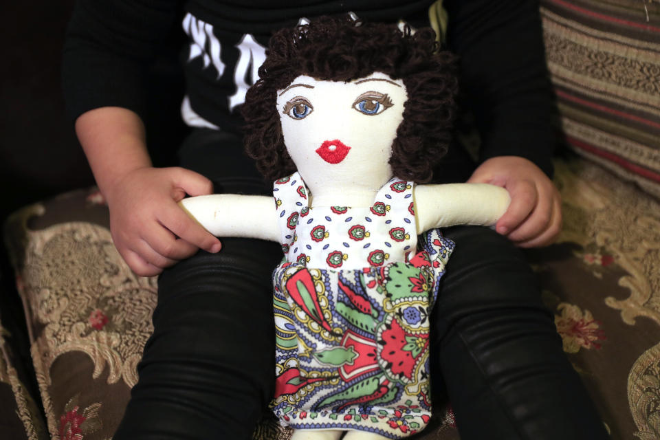 Sima-Rita, whose family home had the windows blown out during August's massive explosion in Beirut, holds her doll at her grandfather's home, in Beirut, Lebanon, Tuesday, Dec. 29, 2020. After the explosion, painter Yolande Labaki made 100 dolls for children affected by the destruction. (AP Photo/Hussein Malla)