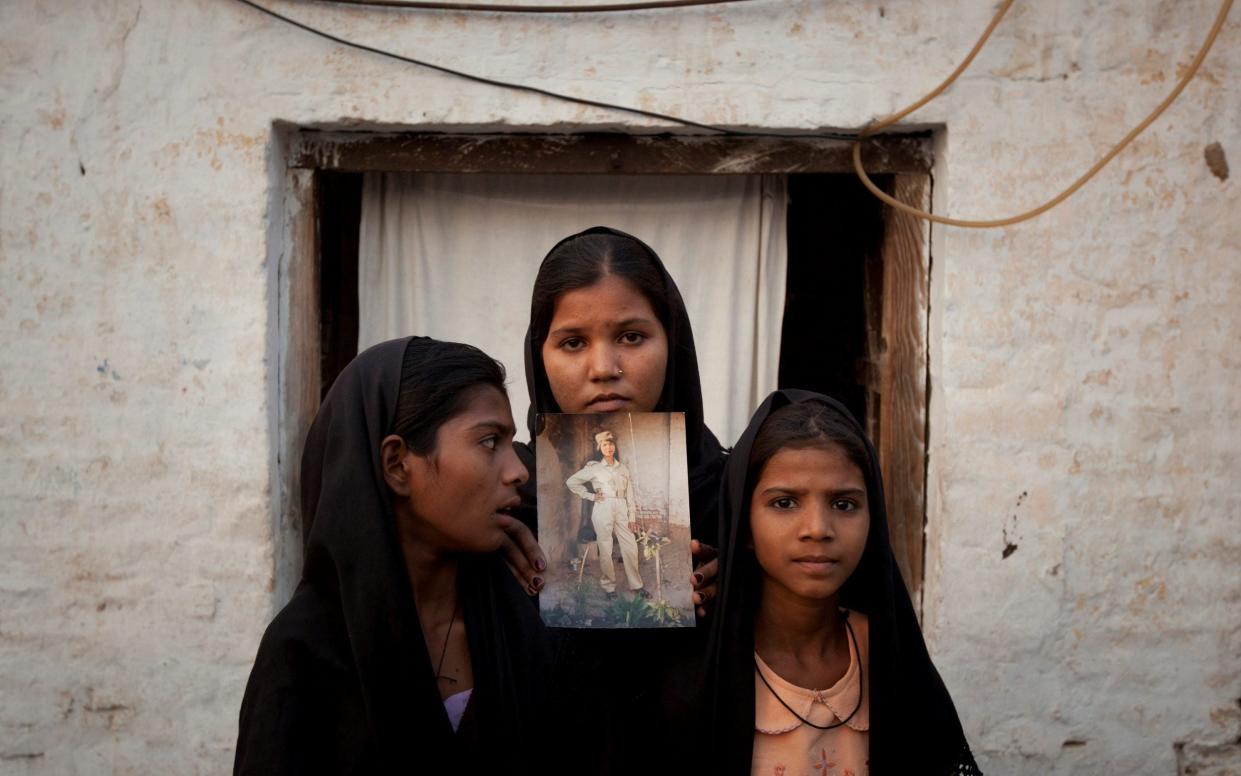 The daughters of Pakistani Christian woman Asia Bibi pose with an image of their mother while standing outside their residence in Sheikhupura located in Pakistan's Punjab Province - REUTERS