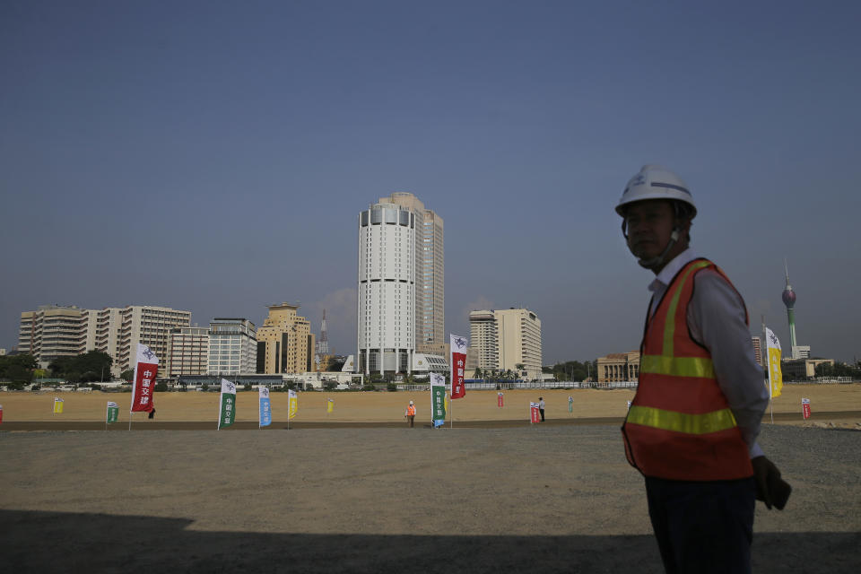 FILE - In this Jan. 2, 2018, file photo, a Chinese construction worker stands on the land that was reclaimed from the Indian Ocean for the Colombo Port City project, that was initiated as part of China's ambitious One Belt One Road initiative on the Galle Face sea promenade in Colombo, Sri Lanka. China's loans to poor countries in Africa and Asia impose unusual secrecy and repayment terms that are hurting their ability to renegotiate debts after the coronavirus pandemic, a group of U.S. and German researchers said in a report Wednesday, March 31, 2021. (AP Photo/Eranga Jayawardena, File)