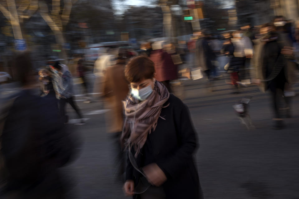 A woman wearing a surgical face mask walks in downtown Barcelona, Spain, Wednesday, Jan. 12, 2022. Italy, Spain and other European countries are re-instating or stiffening mask mandates as their hospitals struggle with mounting numbers of COVID-19 patients. (AP Photo/Emilio Morenatti)