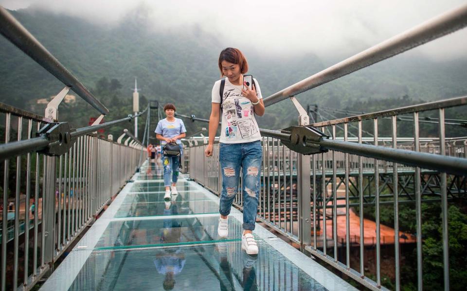 Tourists look on from a glass-bottomed skywalk.