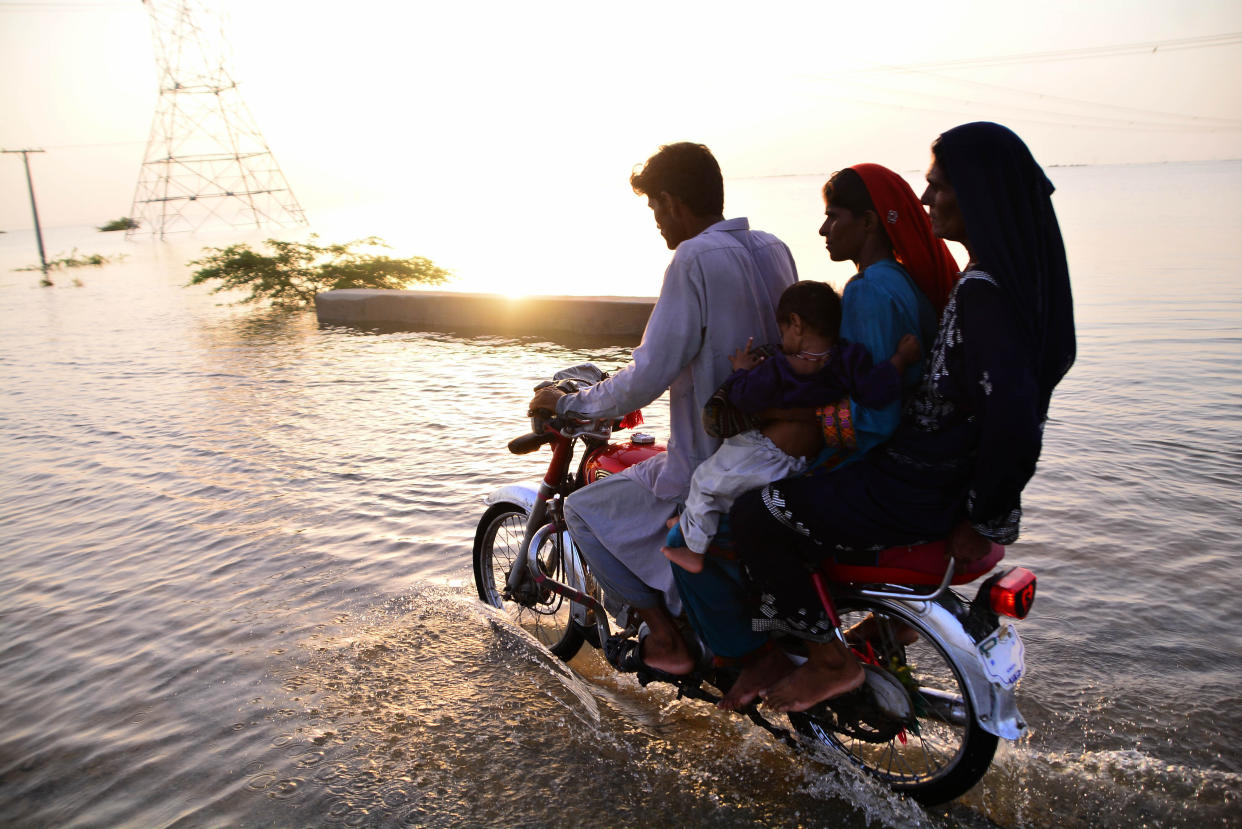 People wade through a flooded area in Sewan Sharif