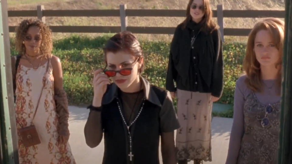 The witches from The Craft standing in front of a bus door.