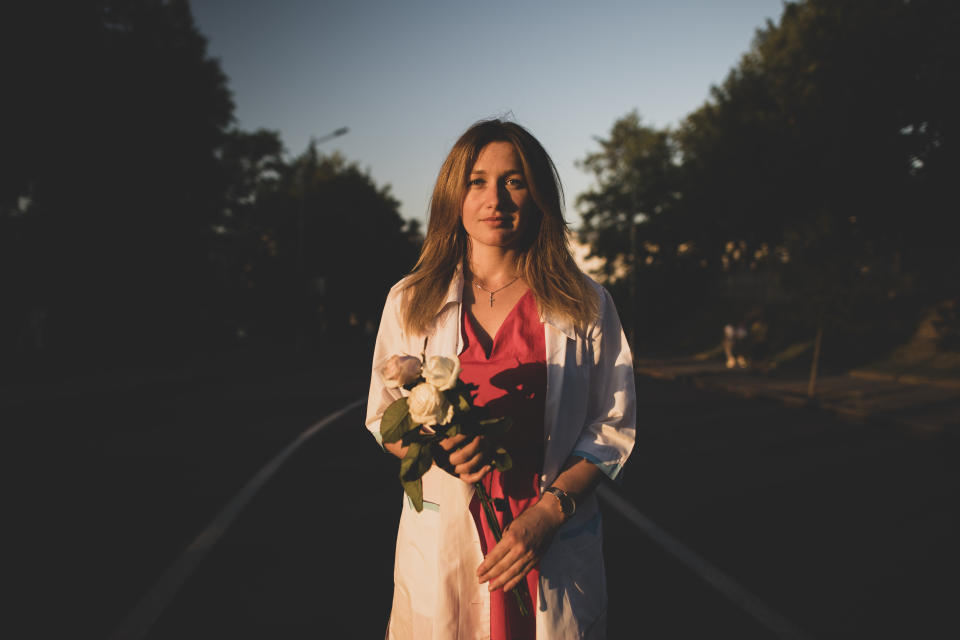 Tatyana, 29, an ambulance paramedic poses for a photo holding white roses during an opposition rally near Independence Square in Minsk, Belarus, Monday, Aug. 17, 2020. Behind each protester in Belarus is a surprising story of awakening. Holding signs or personal tokens of resistance, they described their fears and hopes to The Associated Press, after nearly two weeks of protests against President Alexander Lukashenko's 26-year rule. (AP Photo/Evgeniy Maloletka)