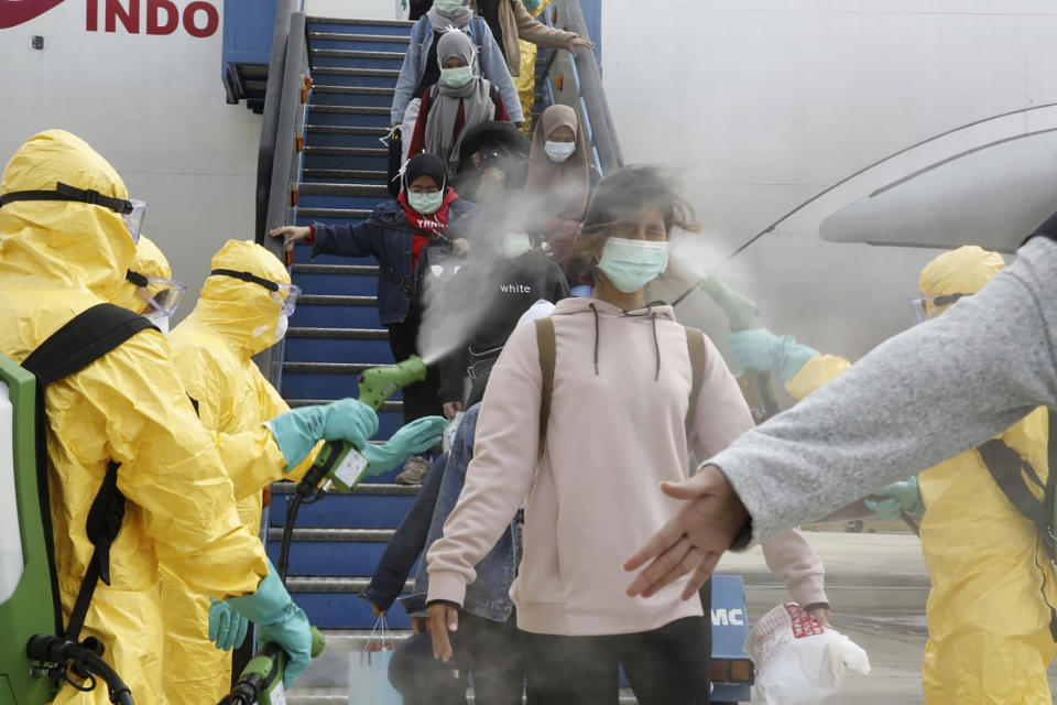 FILE - In this Feb. 2, 2020, file photo released by the Indonesian Foreign Ministry, Indonesians who arrived from Wuhan, China, are sprayed with antiseptic at Hang Nadim Airport in Batam, Indonesia. The virus outbreak that began in China and has spread to more than 20 countries is stretching already-strained public health systems in Asia and beyond, raising questions over whether everyone can get equal access to treatment. (Indonesian Foreign Ministry via AP, File)
