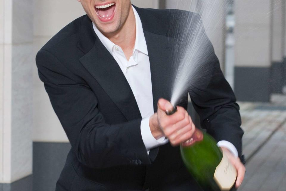 <p>Getty </p> A stock image of a person spraying champagne