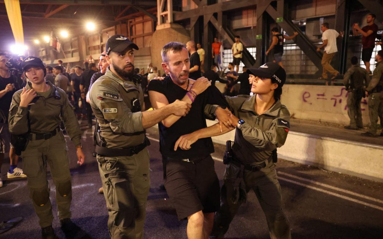 Israeli Police officers detain a protester during clashes following an anti-government rally calling for the release of Israelis held hostage by Palestinian militants in Gaza