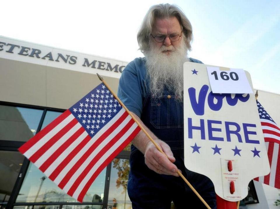 After voting at the Clovis Veterans Memorial District precinct in the 2014 general election, Jimmy Hall places a flag back into a voting stand after it had fallen.