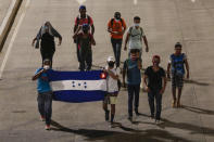 Migrants walk with a Honduran flag, along a highway in hopes of reaching the distant United States, as they depart San Pedro Sula, Honduras, Wednesday, Sept. 30, 2020. Hundreds of migrants have begun walking from this northern Honduras city toward the Guatemala border testing a well-trod migration route now in times of the new coronavirus. (AP Photo/Delmer Martinez)