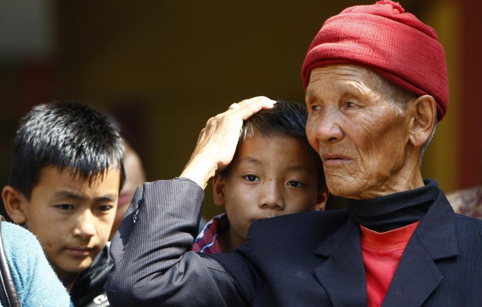 Father and sons of Nepalese mountaineer Ang Kaji Sherpa, killed in an avalanche on Mount Everest, wait for his body to arrive at Sherpa Monastery in Katmandu, Nepal, Saturday, April 19, 2014. Rescuers were searching through piles of snow and ice on the slopes of Mount Everest on Saturday for four Sherpa guides who were buried by an avalanche that killed 12 other Nepalese guides in the deadliest disaster on the world's highest peak. The Sherpa people are one of the main ethnic groups in Nepal's alpine region, and many make their living as climbing guides on Everest and other Himalayan peaks. (AP Photo/Niranjan Shrestha)