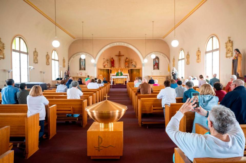A woman takes a photo documenting the final mass at St. Rita of Cascia on Wednesday, June 8, 2022, in Tacoma.