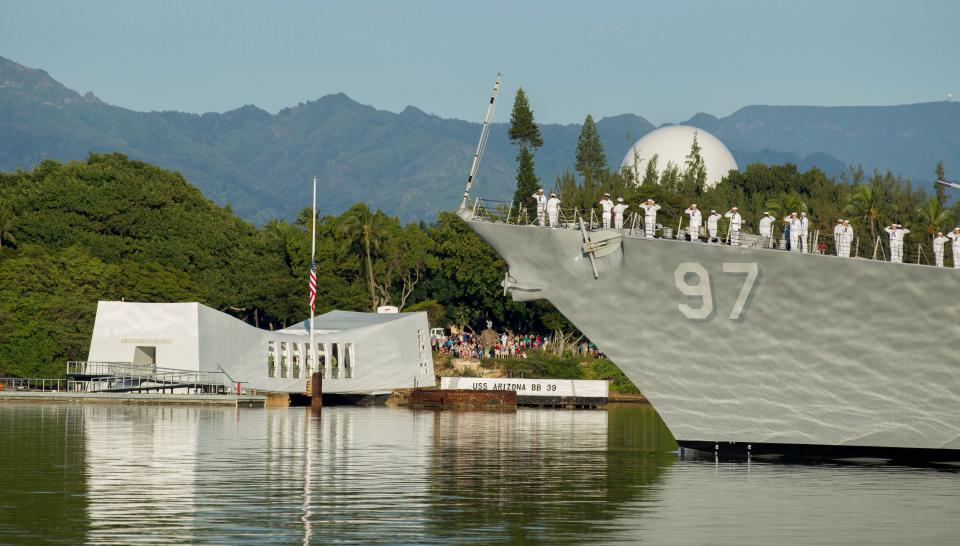 In this Dec. 7, 2016, file photo, sailors on the USS Halsey salute while passing the USS Arizona Memorial during a moment of silence at Pearl Harbor, Hawaii. The bombing of that port sent the U.S. into World War II, a war that took more than 400,000 lives but galvanized the country.