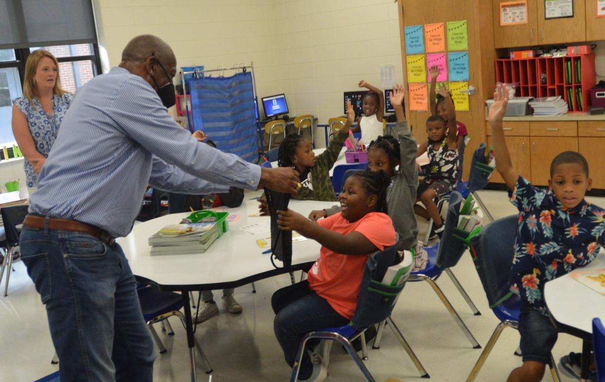 Rev. Daniel Thomas and representatives of the Greater St. Matthew A.M.E. Church Women’s Missionary Society hand out school supplies to the first and second grade at Louisville Academy.