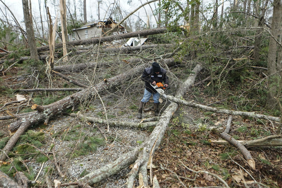 Johnny Martin works to clear downed trees from around a storm damaged home Friday, Jan. 13, 2023, in Jackson, Ga. Powerful storms spawned tornadoes across Georgia Thursday night. (AP Photo/John Bazemore)