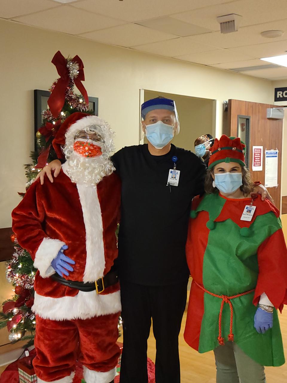Travis Exum visits with Santa and an elf at an Amarillo, Texas, hospital where he went to serve as a registered nurse on a COVID-19 front-line disaster relief team. Despite precautions, Exum contracted the virus and is now dealing with long COVID. Dec. 16, 2020