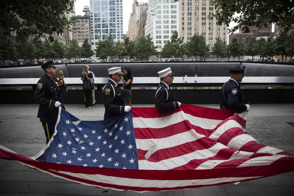 NEW YORK, NY - SEPTEMBER 11: Members of the New York Police Department, Fire Department of New York and Port Authority Police Department carry an American flag past one of the reflecting pools at the beginning of the memorial observances held at the site of the World Trade Center on September 11, 2014 in New York City. This year marks the 13th anniversary of the September 11th terrorist attacks that killed nearly 3,000 people at the World Trade Center, Pentagon and on Flight 93. (Photo by Andrew Burton/Getty Images)