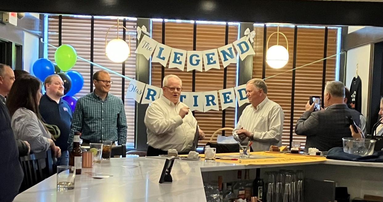 Retiring utilities superintendent Roger Loomis (right) receives retirement congratulations from Newark Mayor Jeff Hall, friends and co-workers Thursday at 1922 On The Square restaurant in downtown Newark.