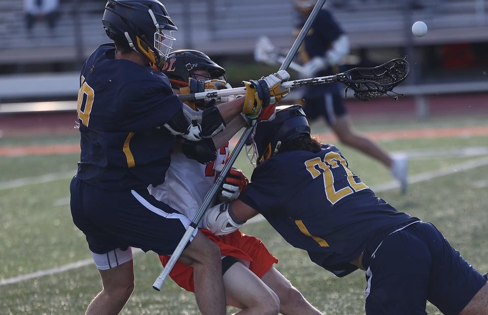 Moeller's Andrew Samoya and  Joe Ginnetti (22) battle Loveland's Jackson Noe( 43) during their lacrosse match, Wednesday, March 23, 2022.