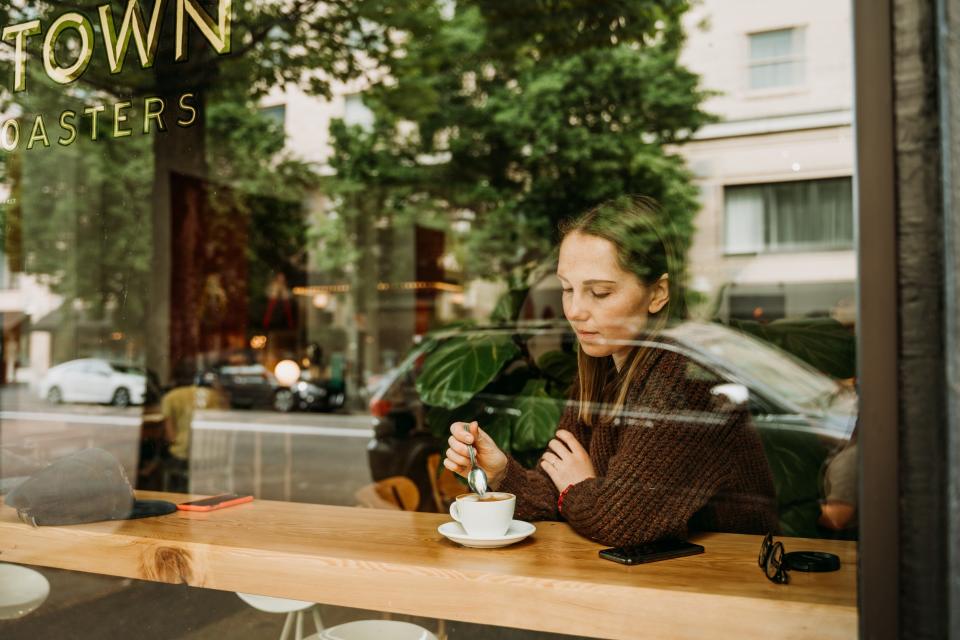 Girl sitting in coffee shop and having a cup of coffee in Portland, OR.