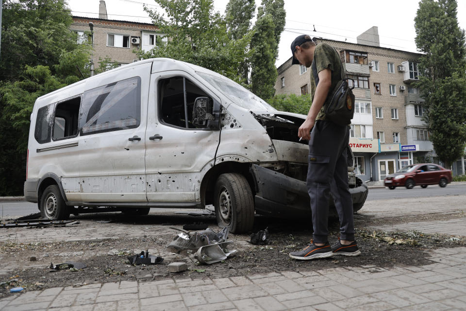 A man inspects a car damaged during shelling in Donetsk, in territory under the government of the Donetsk People's Republic, eastern Ukraine, Wednesday, June 22, 2022. (AP Photo/Alexei Alexandrov)