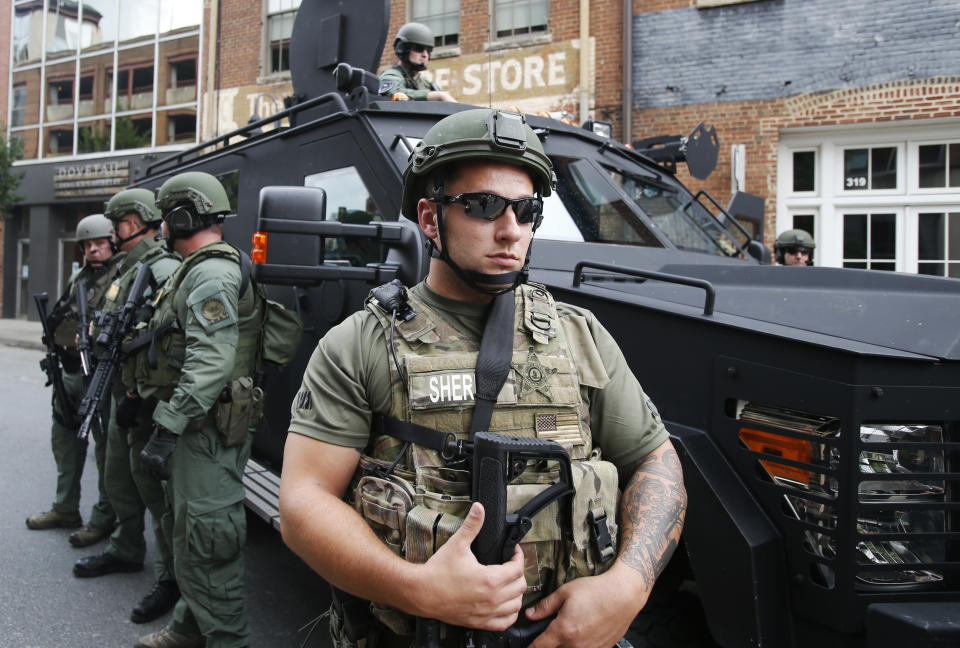 Members of a SWAT team keep an eye on demonstrators marking the one year anniversary of the Unite The Right rally in Charlottesville, Va., Sunday, Aug. 12, 2018. (AP Photo/Steve Helber)