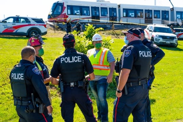 Police officers speak with an OC Transpo official on Sept. 19, 2021, not long after an LRT train left the Confederation Line tracks near Tremblay station. No one was injured in the derailment. (Nicholas Cleroux/Radio-Canada - image credit)