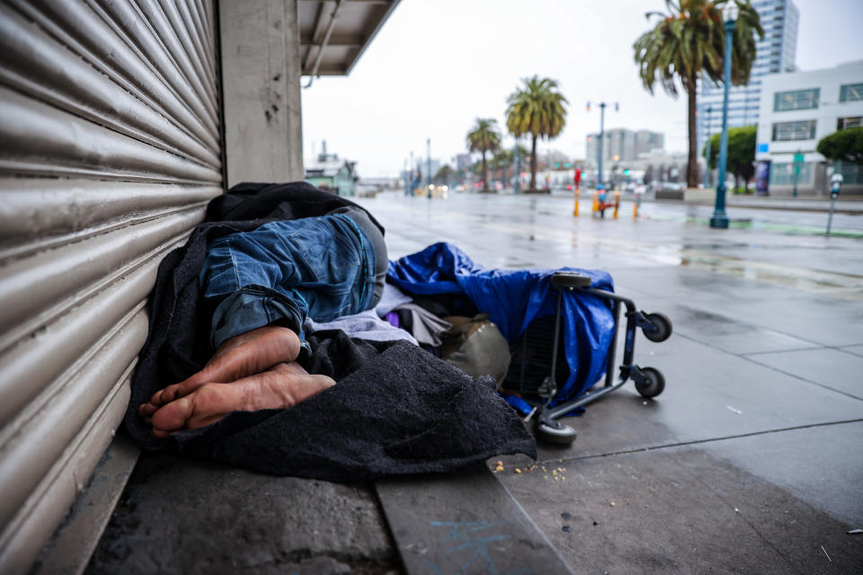 A homeless man sleeps in front of a business gate in San Francisco.