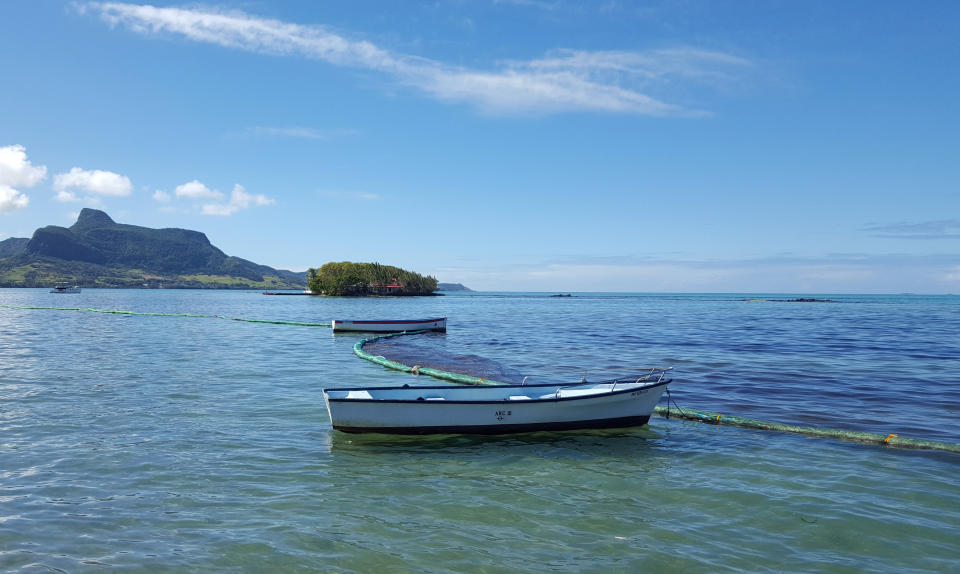 This photo taken and provided by Sophie Seneque, shows a boom, a temporary floating barrier used to contain the oil spill in Mahebourg Waterfront, Mauritius, Saturday Aug. 8, 2020, after it leaked from the MV Wakashio, a bulk carrier ship that recently ran aground off the southeast coast of Mauritius. Thousands of students, environmental activists and residents of Mauritius are working around the clock to reduce the damage done to the Indian Ocean island from an oil spill after a ship ran aground on a coral reef. Shipping officials said an estimated 1 ton of oil from the Japanese ship’s cargo of 4 tons has escaped into the sea. Workers were trying to stop more oil from leaking, but with high winds and rough seas on Sunday there were reports of new cracks in the ship's hull. (Sophie Seneque via AP)