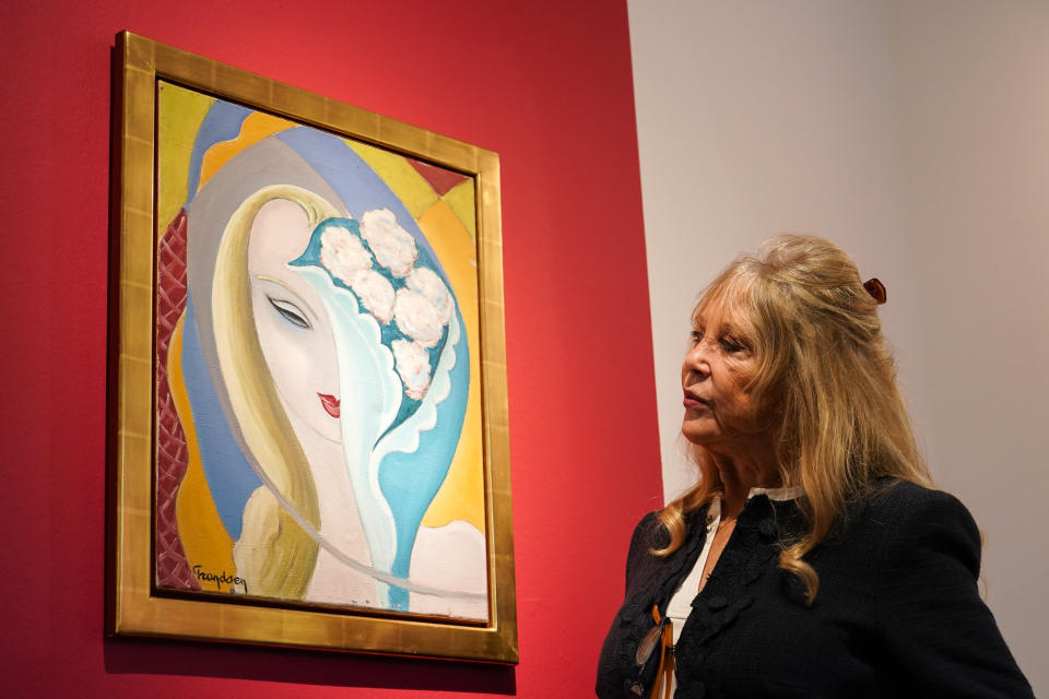 Pattie Boyd poses next to the original artwork by E. Frandsen De Schomberg, used for the cover of Derek and the Dominoes album 'Layla and Other Assorted Love Songs' as part of The Pattie Boyd Collection at Christie's, in London, Thursday, March 14, 2024. The artwork is estimated to sell £40,000-60,000. (AP Photo/Alberto Pezzali)