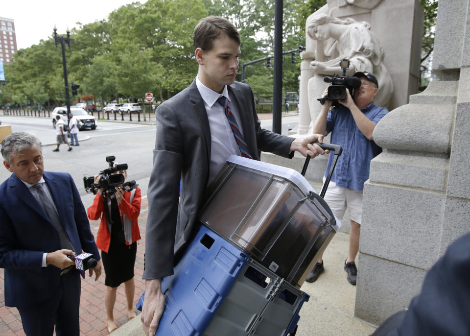FILE - Nathan Carman, center, carries documents as he arrives at federal court, Tuesday, Aug. 13, 2019, in Providence, R.I. Carman, who was found floating on a raft in the ocean off the coast of Rhode Island in 2016 after his boat sank, has been indicted on charges alleging he killed his mother at sea to inherit the family's estate, according to the indictment unsealed Tuesday, May 10, 2022. (AP Photo/Steven Senne, File)