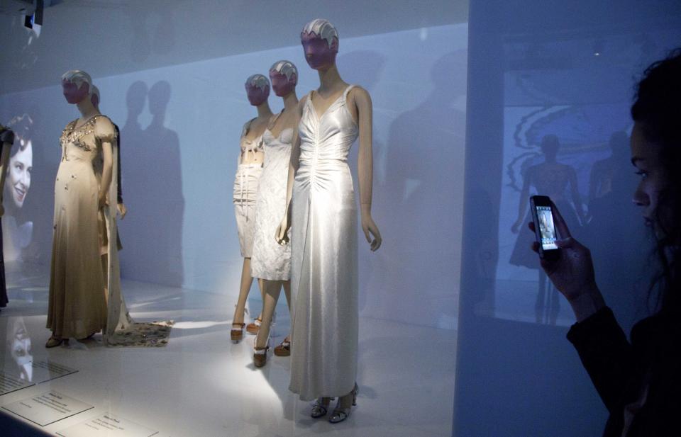 A woman photographs a display of fashions by Elsa Schiaparelli and Miuccia Prada at the Metropolitan Museum of Art, Monday, May 7, 2012 in New York. The  show "Schiaparelli and Prada, Impossible Conversations," opens May 10 and continues through Aug. 19. (AP Photo/Mark Lennihan)