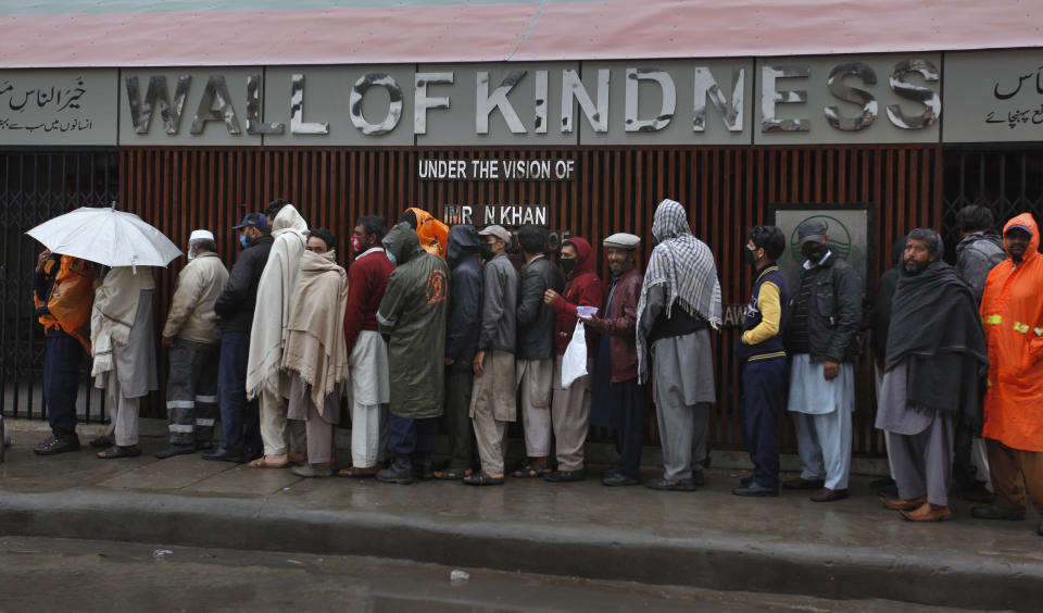 Daily wage workers left jobless due to travel restrictions aimed at containing the coronavirus, wait their turn to receive free food in Rawalpindi, Pakistan, Tuesday, March 24, 2020. According to the World Health Organization, most people recover from the virus in about two to six weeks, depending on the severity of the illness. (AP Photo/Anjum Naveed)