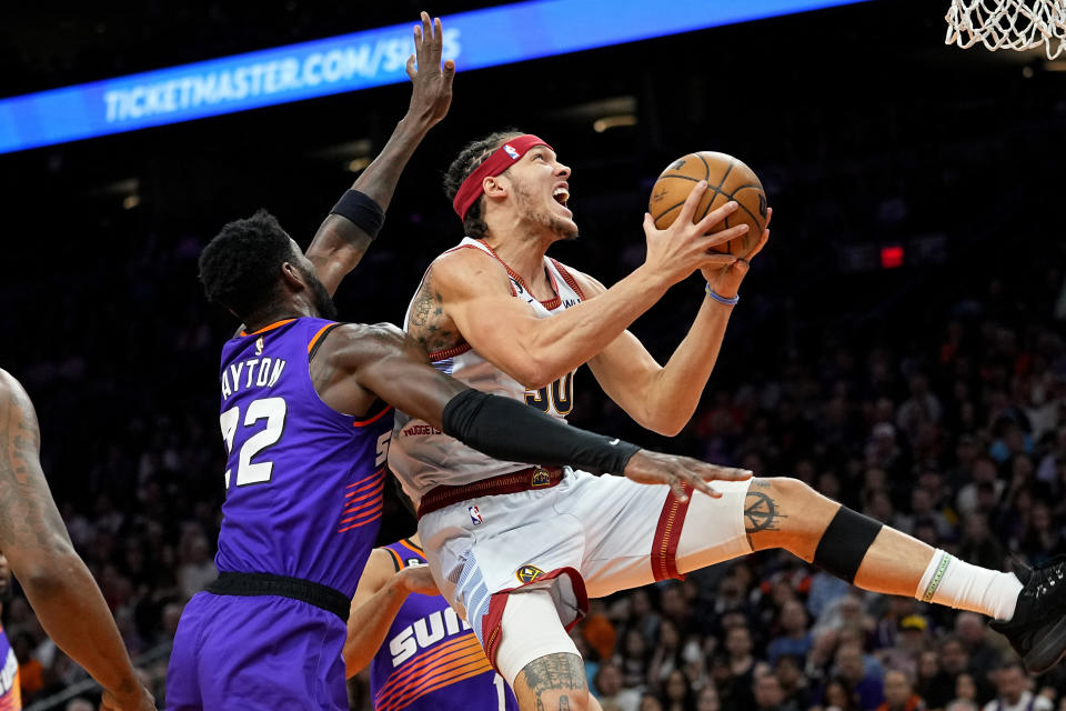 Denver Nuggets forward Aaron Gordon is fouled by Phoenix Suns center Deandre Ayton (22) during the first half of an NBA basketball game, Friday, March 31, 2023, in Phoenix. (AP Photo/Matt York)