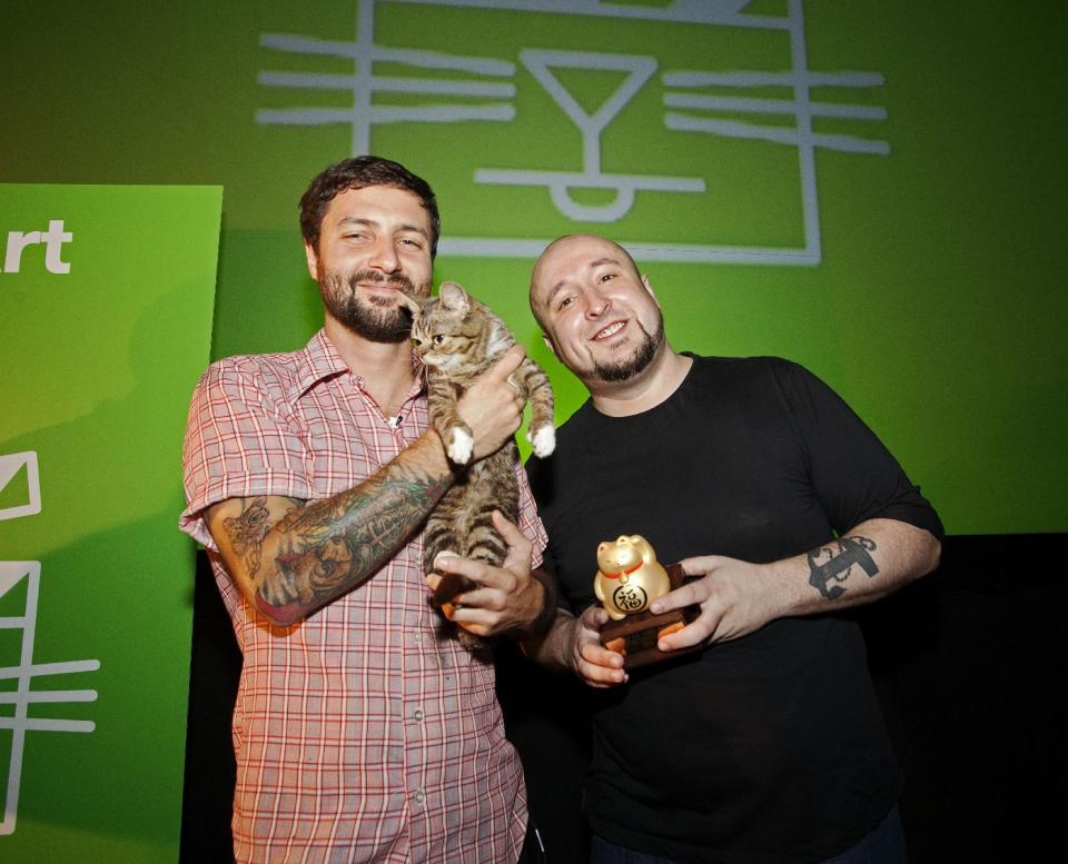 In this Aug. 30, 2012 publicity photo provided by the Walker Art Center, festival attendee, Mike Bridavsky and his cat Lil Bub, left, pose with Golden Kitty Award-winner William Braden, at the Walker Art Center Internet Cat Video Festival in Minneapolis. (AP Photo/Walker Art Center, Gene Pittman)