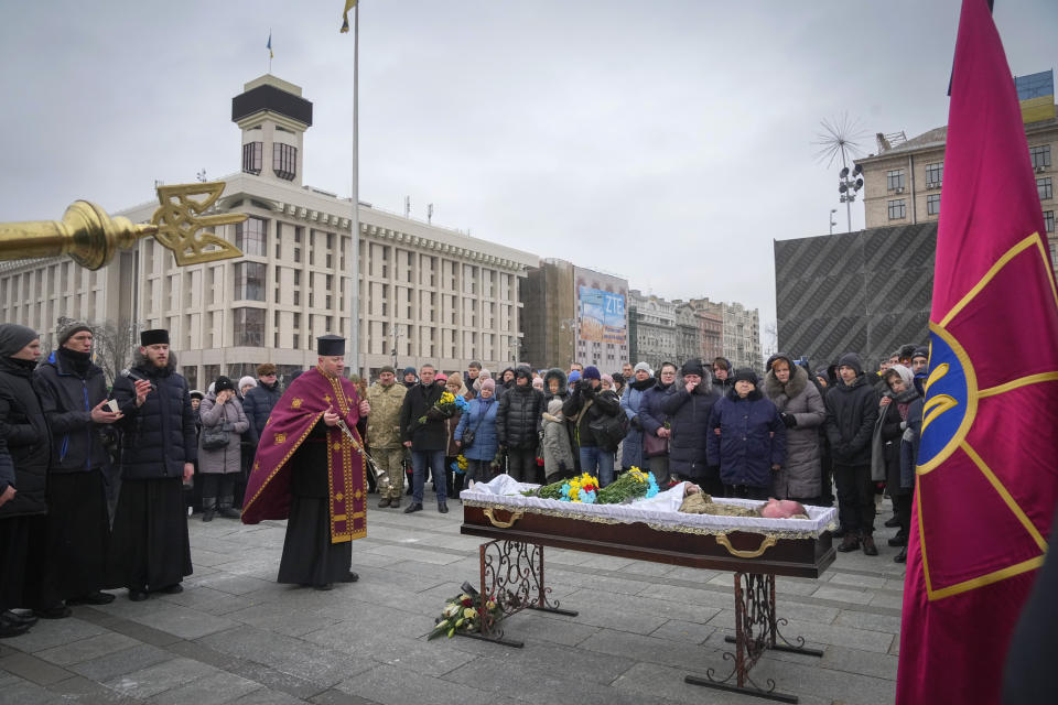 A priest leads a farewell ceremony near the coffin of Ukrainian soldier Oleh Yurchenko killed in a battlefield with Russian forces in the Donetsk region during a commemoration ceremony in Independence Square in Kyiv, Ukraine, Sunday, Jan. 8, 2023. (AP Photo/Efrem Lukatsky)