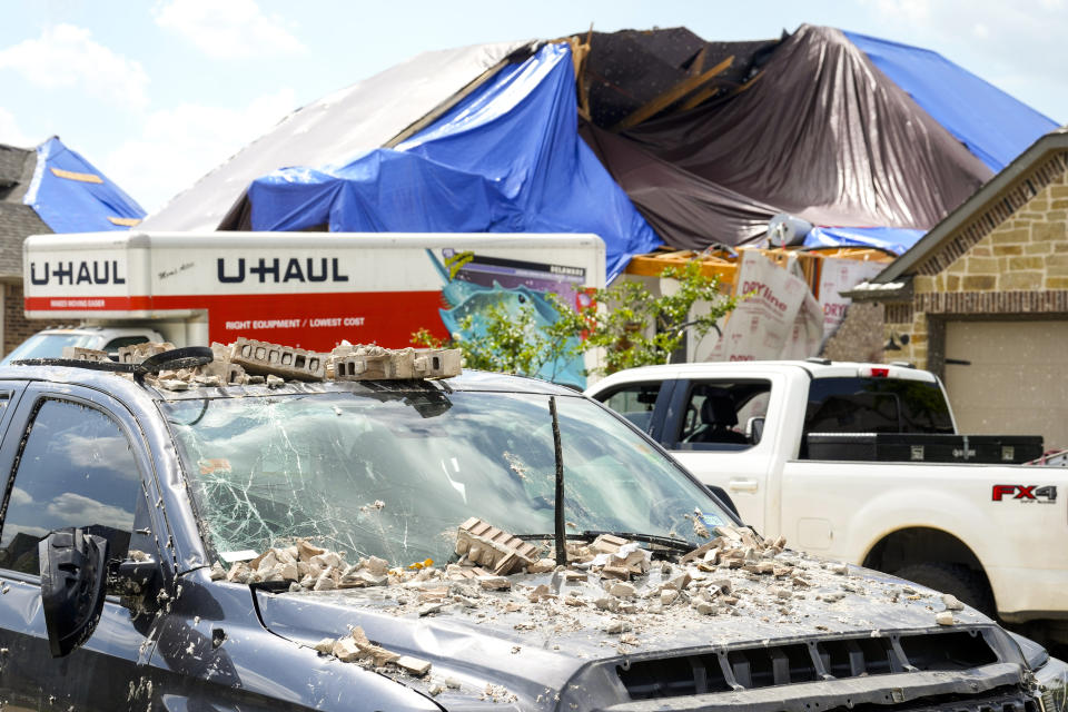 A truck is covered in debris as a families in Bridgeland begin to recover from and clean up storm damage on Sunday, May 19, 2024, in Cypress, Texas. The suburban Houston area of Bridgeland suffered major damage last week after a line of powerful storms, that included a confirmed tornado, swept through the area. (Brett Coomer/Houston Chronicle via AP)