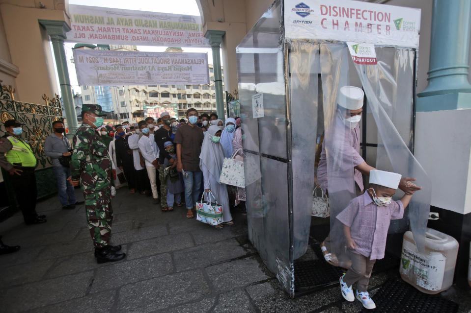 Muslims walk through a disinfection chamber installed to curb the spread of coronavirus outbreak as they enter Al Mashun Great Mosque compound to attend an Eid al-Fitr prayer in Medan, North Sumatra, Indonesia, Thursday, May 13, 2021. (AP Photo/Binsar Bakkara)