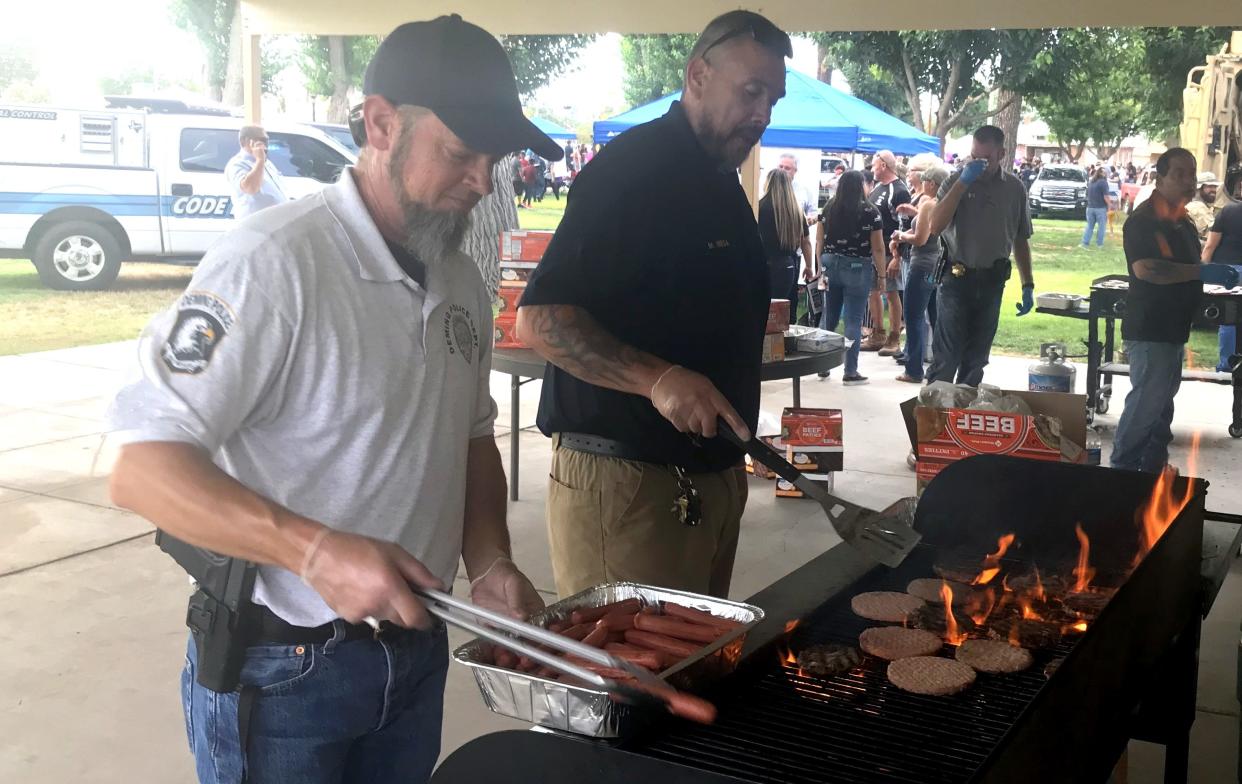 From left, Deming Police Captain Clint Hogan and code enforcer Manny Mesa grilled hamburger patties and hot dogs during National Night Out at the Luna County Courthouse Park.