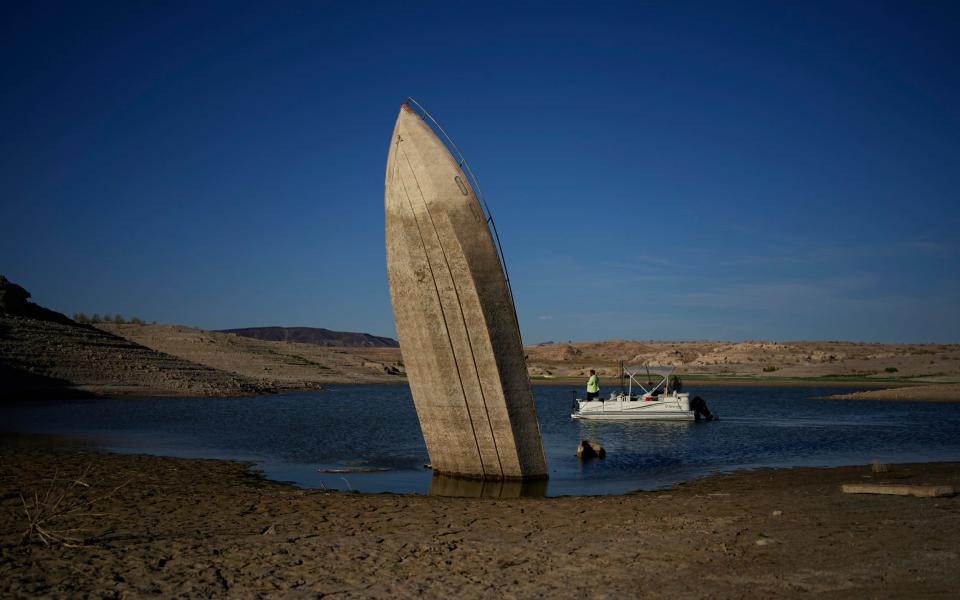 A formerly sunken boat sits upright into the air with its stern stuck in the mud along the shoreline of Lake Mead at the Lake Mead National Recreation Area, Friday, June 10, 2022, near Boulder City, Nev. Lake Mead water has dropped to levels it hasn't been since the lake initially filled over 80 years ago. (AP Photo/John Locher) - AP Photo/John Locher