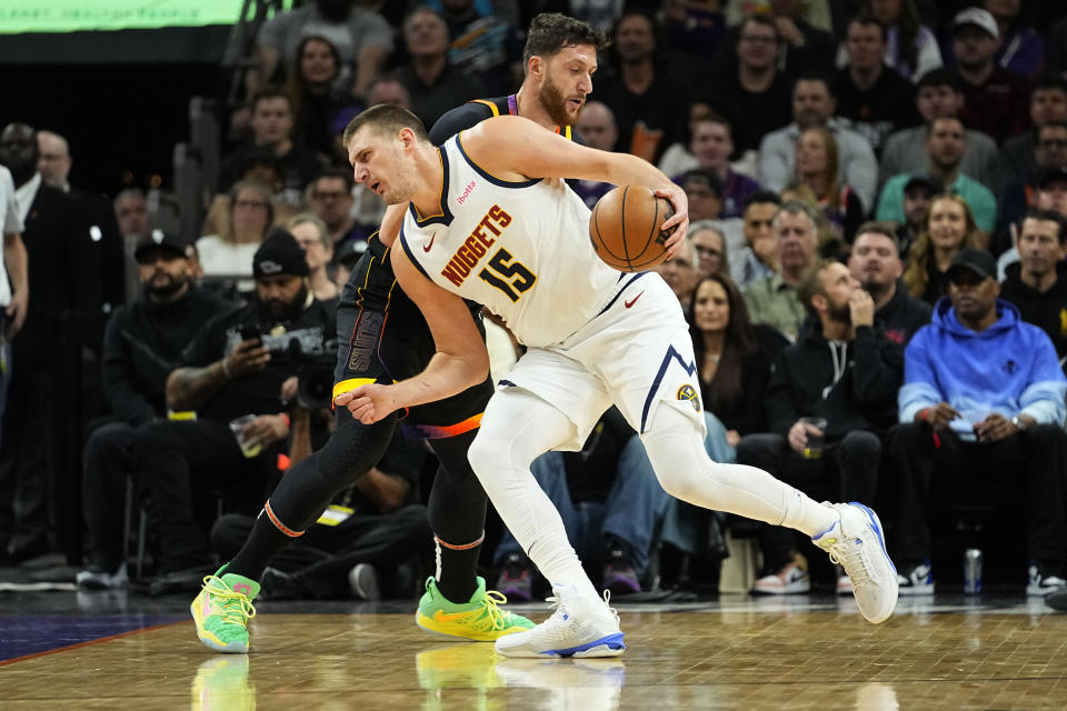 Denver Nuggets center Nikola Jokic (15) backs down Phoenix Suns center Jusuf Nurkic during the first half of an NBA basketball game, Friday, Dec. 1, 2023, in Phoenix. (AP Photo/Matt York)